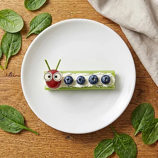 A single Little Crawlers celery caterpillar with cream cheese, blueberry body dots, a grape head, googly eyes and antennae